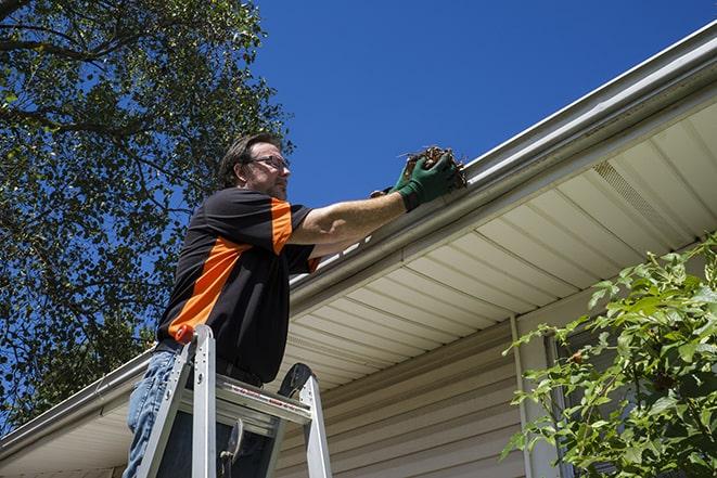 a worker fixing a broken gutter on a residential home in Blue Point